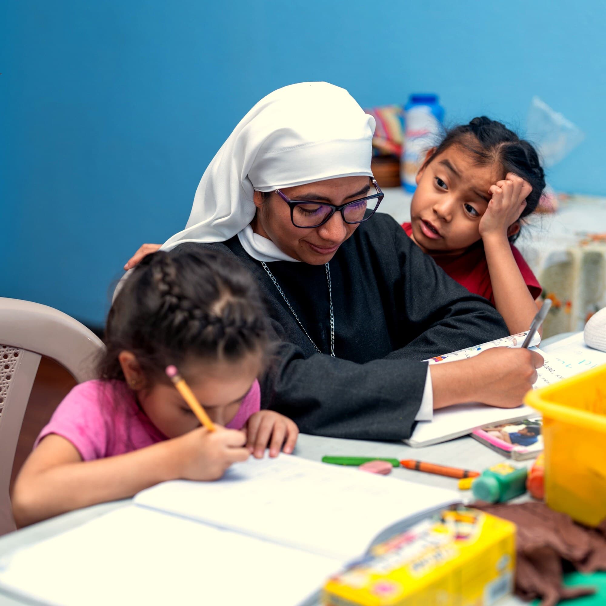 Hermana acompañando a niñas en sus tareas